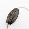 Gros plan d'une perle ovale noire gravée de motifs dorés